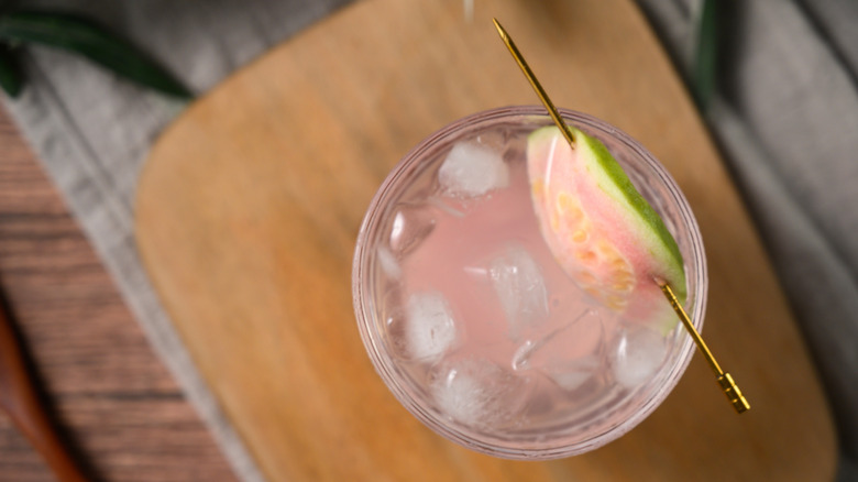 Overhead view of a glass of guava soda with a slice of the fruit as a garnish