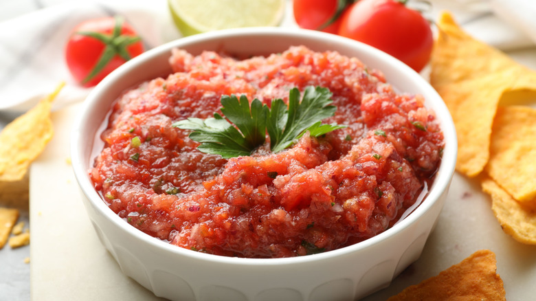 Small white dish of salsa with fresh ingredients and tortilla chips