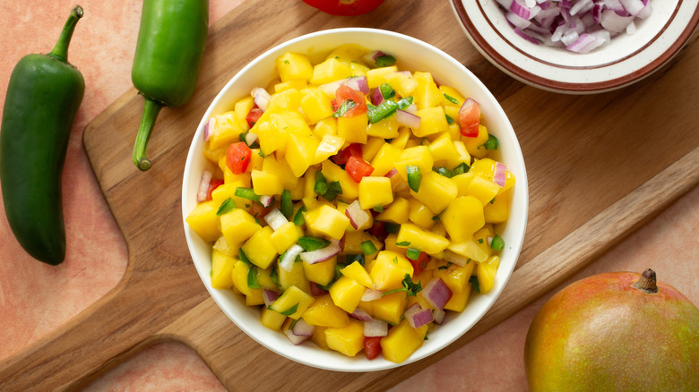 A bowl of mango salsa with many ingredients including jalapeños and raw onions