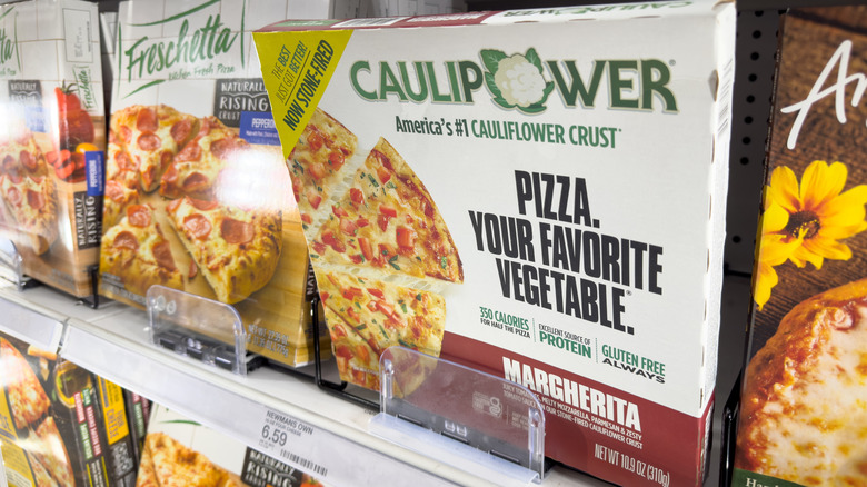 Caulipower Cauliflower Crust Margherita pizza sits upright on a freezer shelf with other frozen pizzas around it