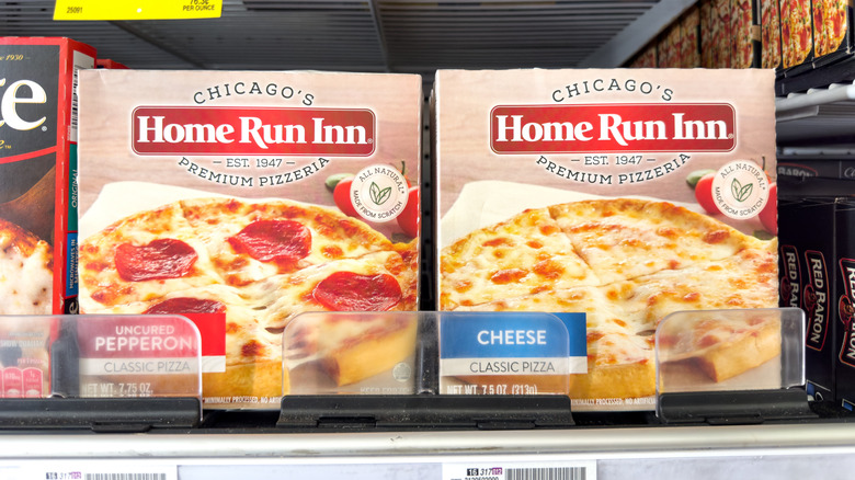 Home Run Inn cheese and pepperoni pizzas in boxes sit side by side on a store freezer shelf