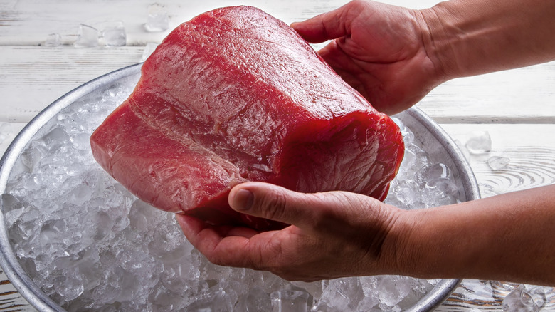 a block of tuna held over a bowl of ice