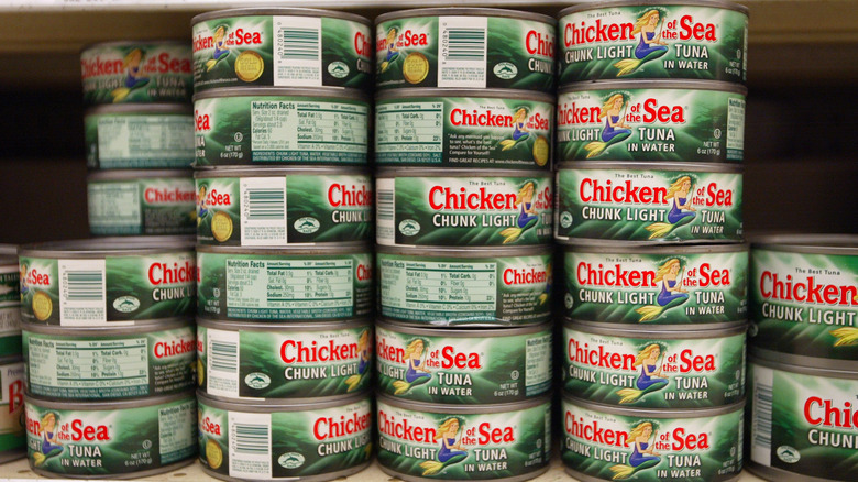 Cans of Chicken of the Sea chunk light tuna in water stacked on a grocery store shelf