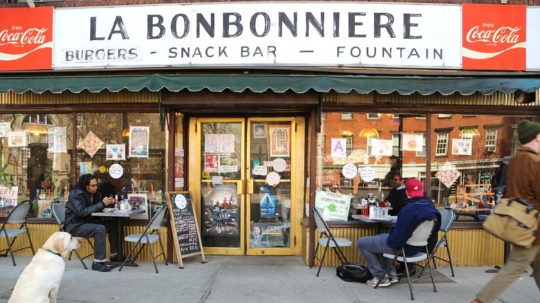 The exterior of La Bononierre, lots of sign in the window, people sitting outside and a labrador dog