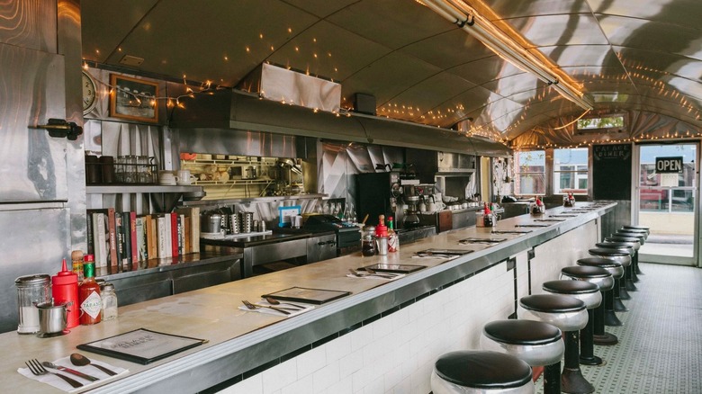 The interior of Palace Diner, a chrome counter with chrome bar stools and fairy lights on the ceiling