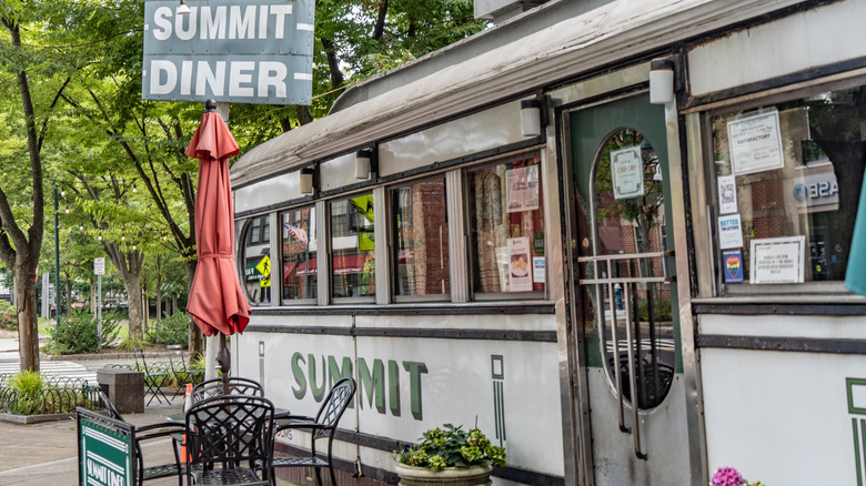 The exterior of Summit Diner, it looks like a vintage train car, it has tables and chairs outside