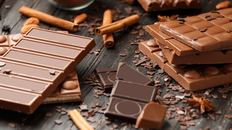 An assortment of chocolate bars, candies, and chips on a wooden surface