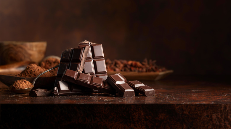 A broken bar of dark chocolate on a wooden surface