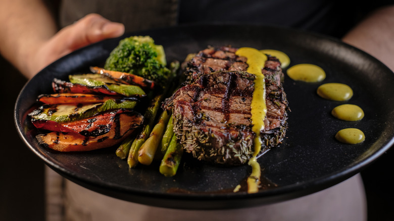 chef holding steak on a plate 