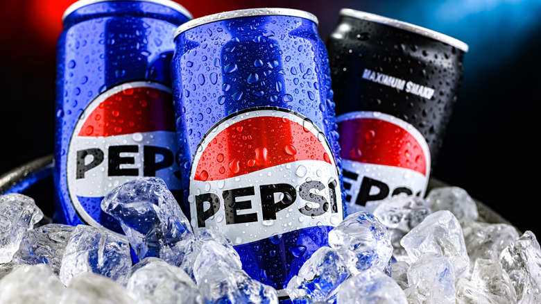 Three Pepsi cans in ice.