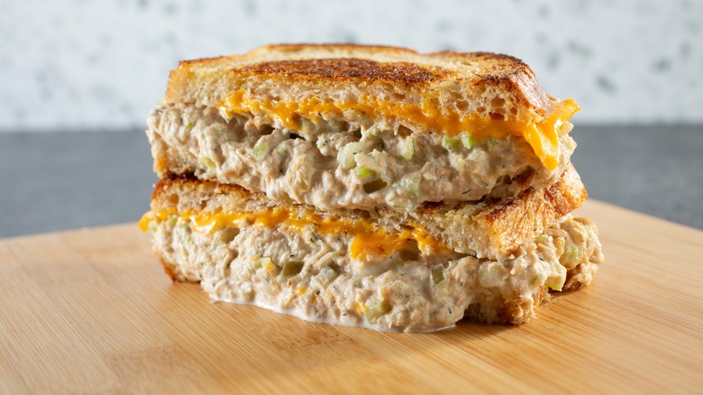 Stacked and sliced tuna melt sandwich on wooden cutting baord