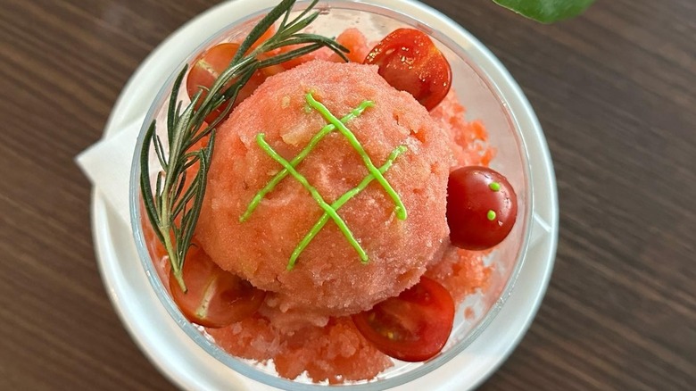 A bright green avocado-cream pesto drizzled onto fresh tomato sorbet with a stem of rosemary.