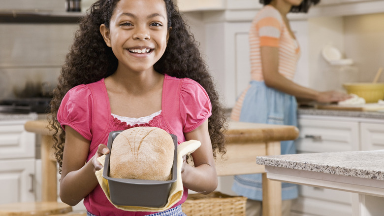 Happy child holding freshly baked bread in kitchen