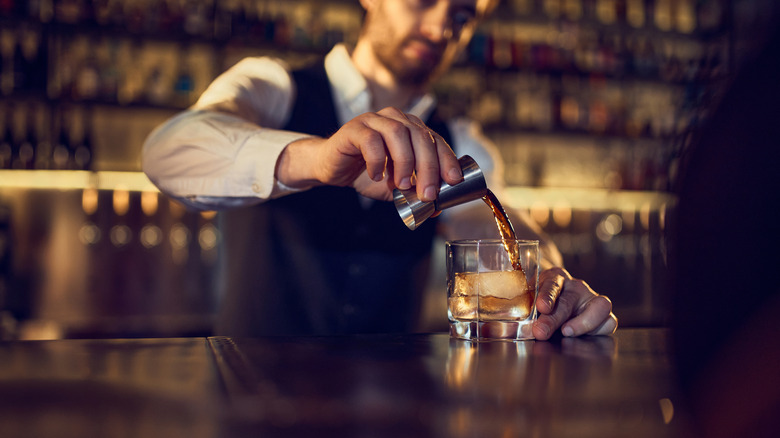 Bartender pouring a spirit into a glass.