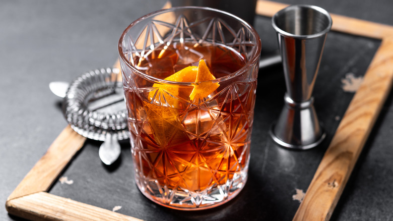 Old fashioned cocktail served alongside bartending tools.
