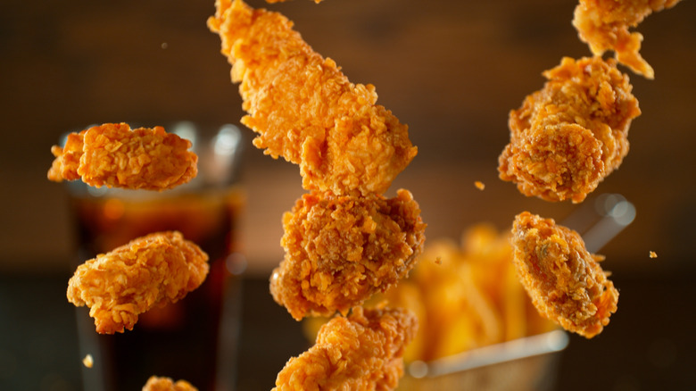 Pieces of fried chicken fly up in the air, presumably having been tossed by an unseen hand