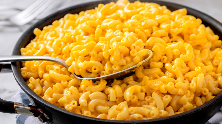 Spoon in a pan of mac and cheese on a table