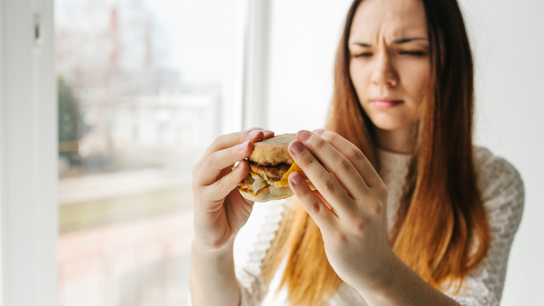A diner stares suspiciously at their fast food burger.
