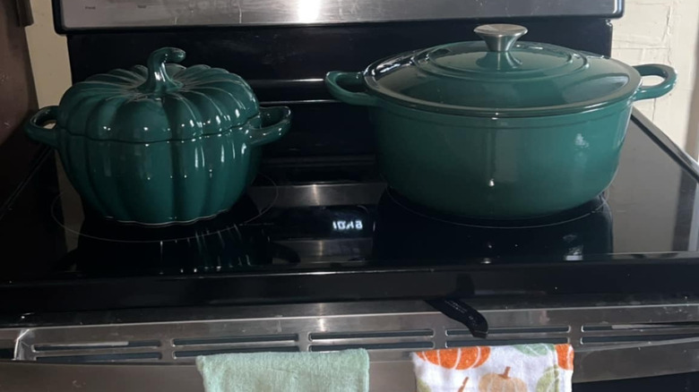 An Aldi casserole dish and dutch oven sit on a black stove