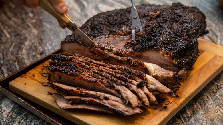 Smoked brisket being sliced on cutting board