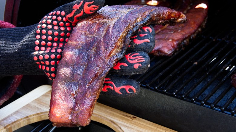 A hand performs the bend test on ribs check for doneness