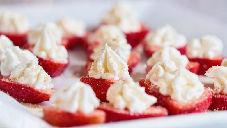 Strawberries cut in half with mounds of cheesecake filling and sugar sprinkles