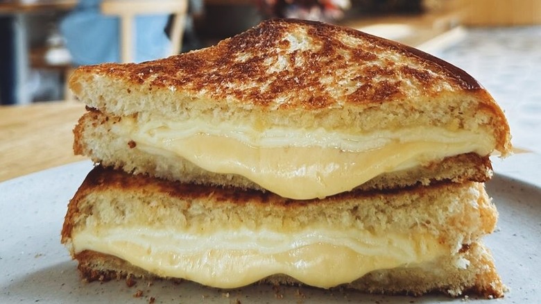 A grilled cheese sandwich made with brioche bread oozes cheese