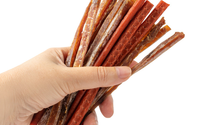 A hand holding a bunch of meat sticks