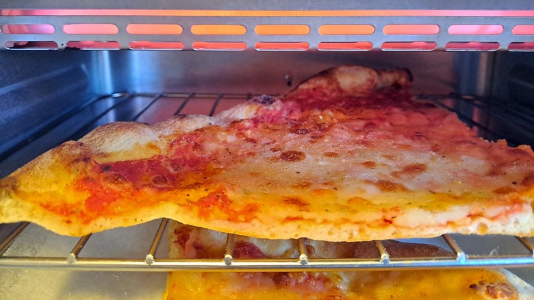 Slice of cheese pizza in toaster oven