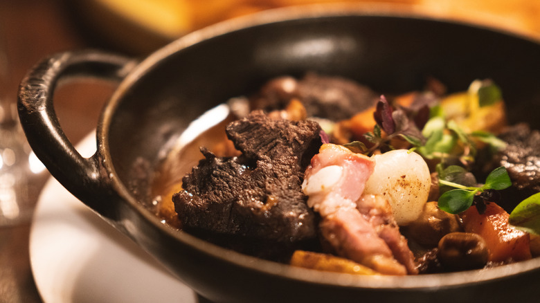 French dish beef bourguignon in a black serving dish
