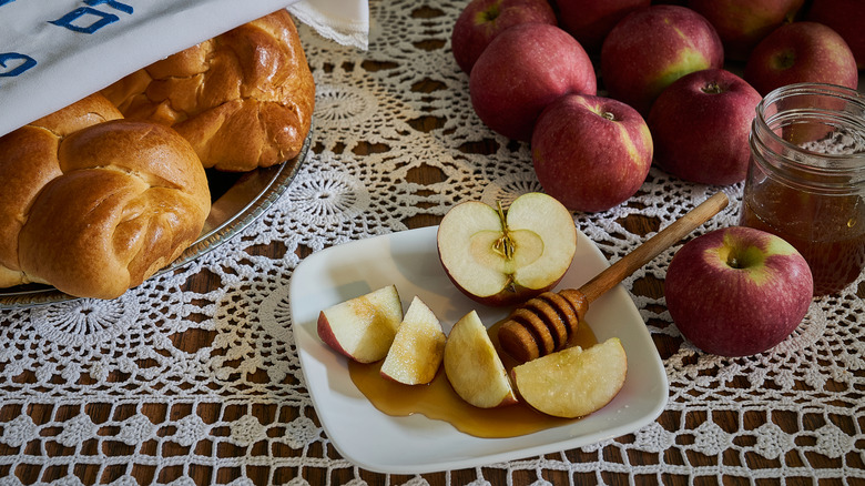 Rosh Hashanah holiday table has apples, honey, and covered challah bread.