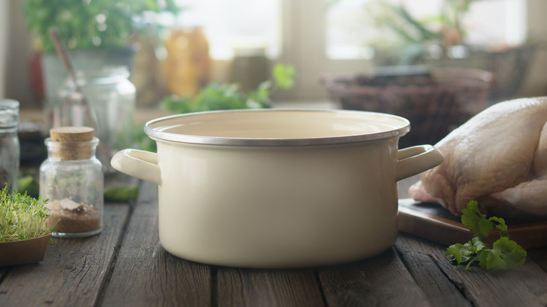 Cream cookware on a wooden table surrounded by ingredients