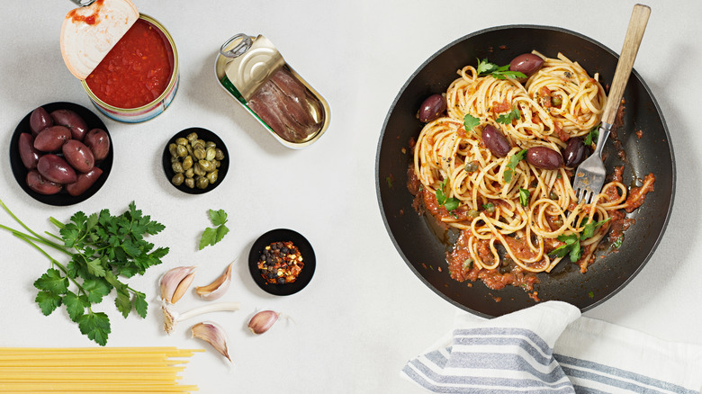 bowl of puttanesca with ingredients laid out