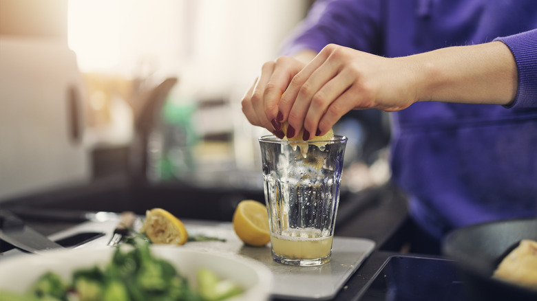 juicing lemon into a glass in a kitchen
