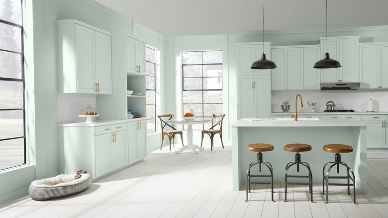 A bright kitchen features a small island with stools and mint green cabinetry