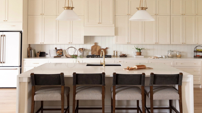 A kitchen with natural light streaming in features off-white cabinetry
