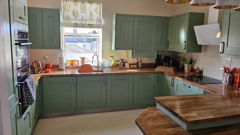 A homey kitchen features light green cabinetry