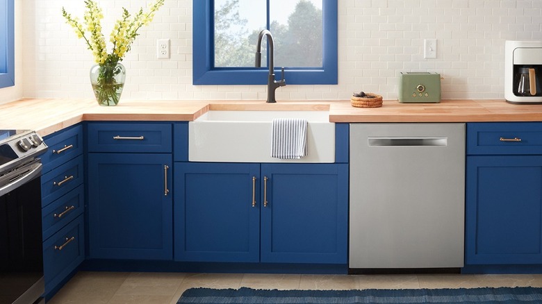 A kitchen features woodblock countertops and deep blue cabinetry