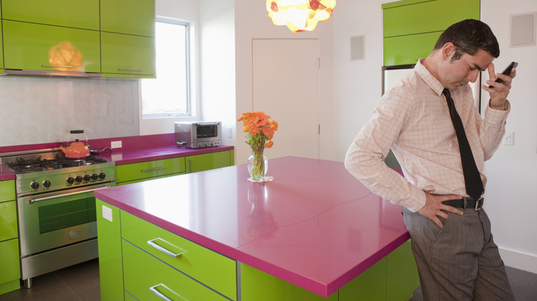 a tired homeowner stands in a bright green and pink colors