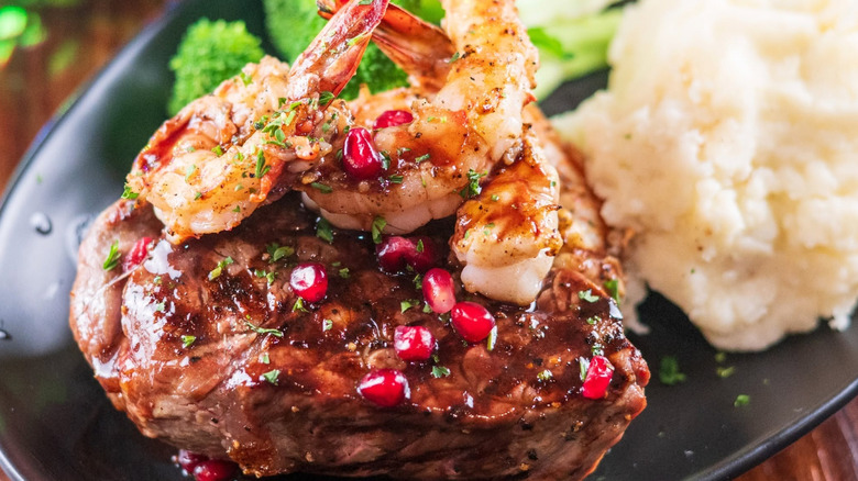 Steak with shrimp on top of it alongside mashed potatoes and broccoli from Black Angus Steakhouse.