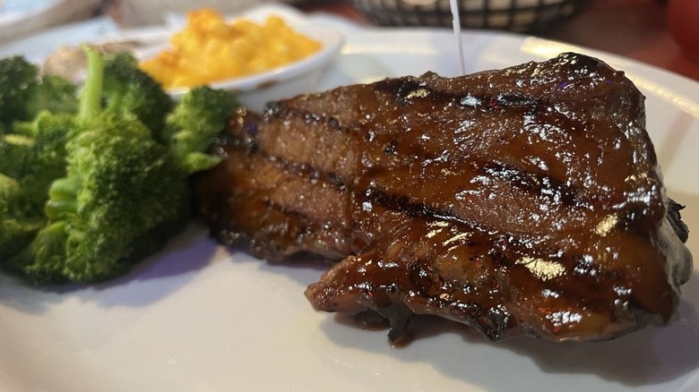 Barbecue steak on a plate next to broccoli and a bowl of corn at Original Roadhouse Grill.