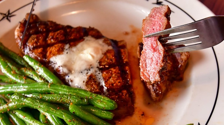 Sliced steak on a plate with seasoned green beans at Saltgrass Steak House.