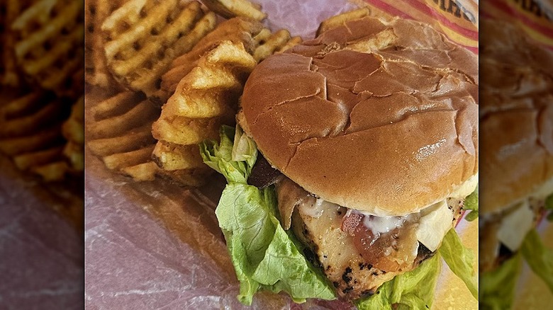 A Carl's Jr. Charbroiled Chicken Club Sandwich sits next to waffle fries