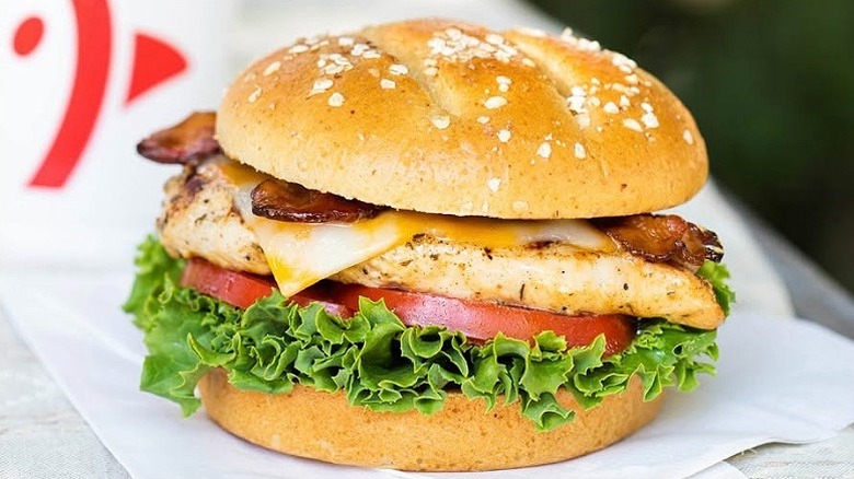 A Chick-fil-A grilled chicken club sits on a wooden table