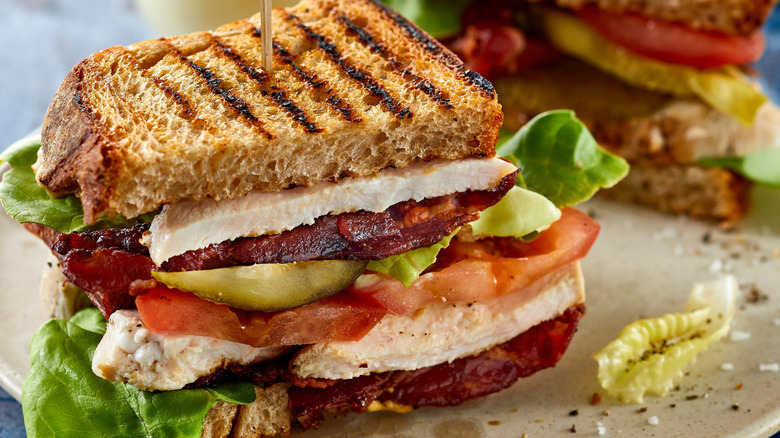 A grilled chicken club sandwich with a toothpick holding it together