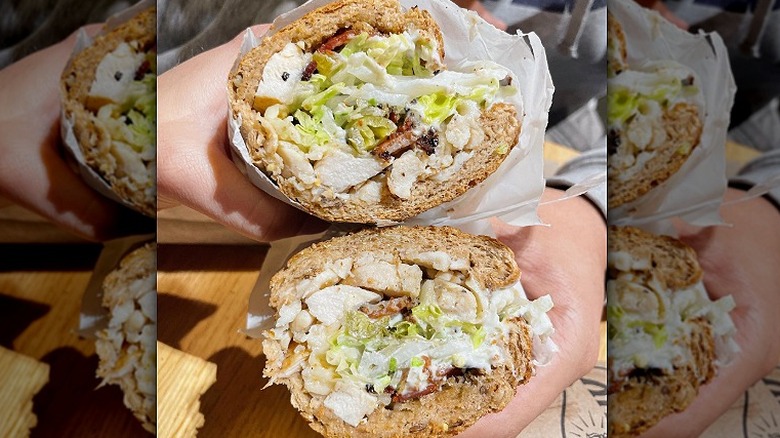Two halves of a chicken club sandwich from Potbelly Sandwich Works are held up on a sunny day