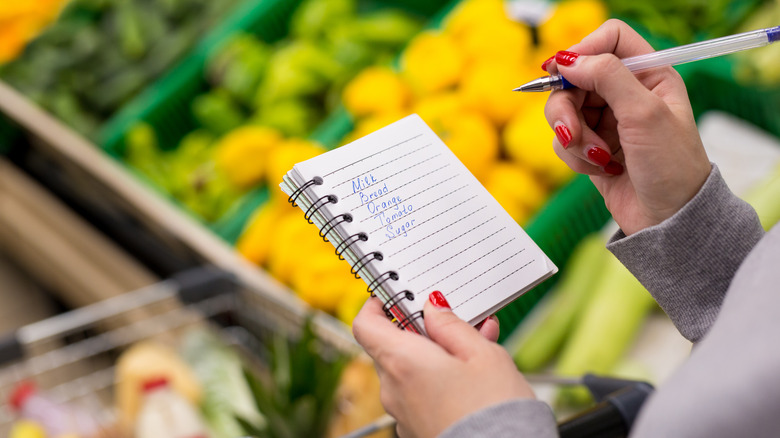 Woman with notebook and pen making a list in grocery store