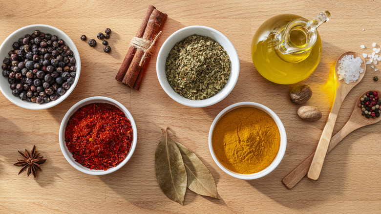 Bowls filled with spices and herbs shot from above on wood background
