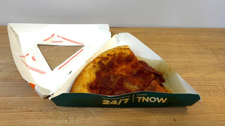 A slice of Ultimate Pepperoni Pizza from 7-Eleven in a to-go container.