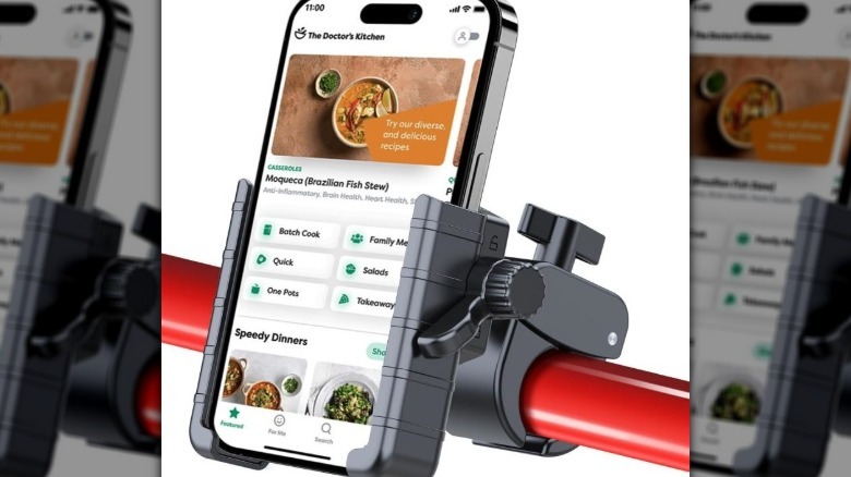 Black plastic phone holder clamped on a red bar